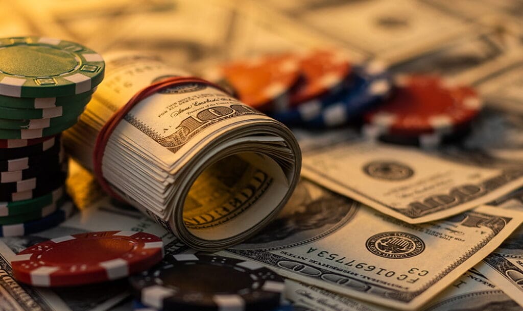 Cash and casino chips on a table. The casino chips are green, red and black.