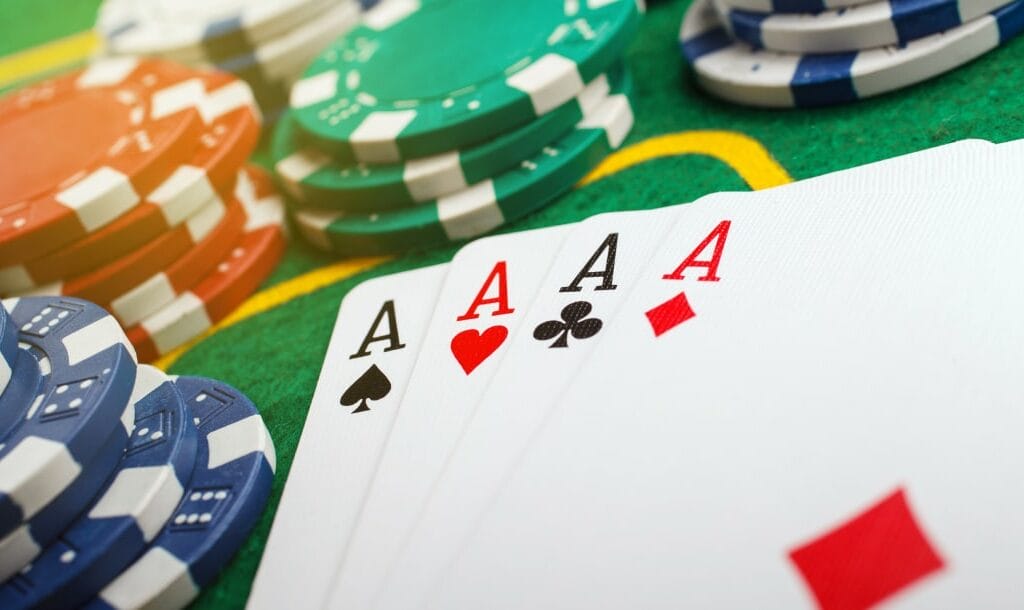 A closeup of a full suit of Aces, blue, red, green, and white poker chips arranged on a poker table.