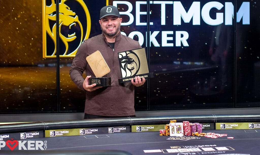 Daniel Maor smiles as he holds awards at a poker table, with chips stacked and a "BetMGM POKER" logo backdrop.