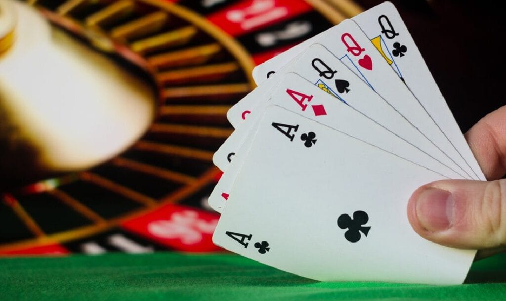 someone-playing-poker-in-front-of-roulette-wheel-holding-full-house