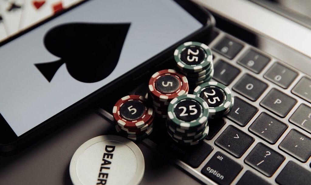 poker-chips-on-a-keyboard-next-to-a-smart-phone-displaying-a-spade