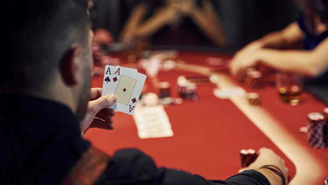 A view from behind a poker player who has two ace cards in his hand
