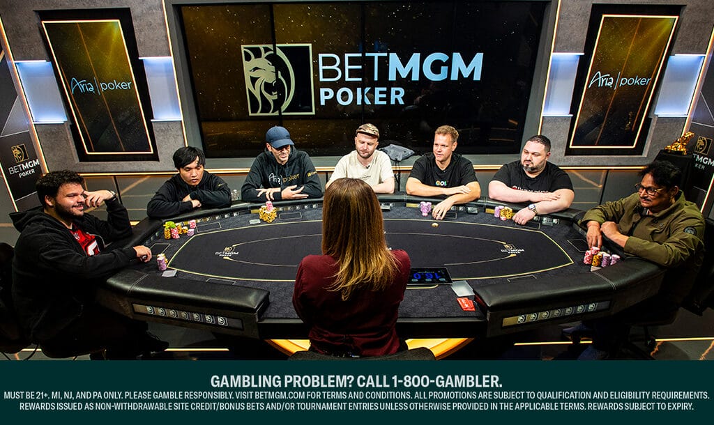 Seven poker players seated around a black felt poker table at the Aria Poker room during a BetMGM Poker event, facing a female dealer. Stacks of colorful poker chips are in front of each player, with large BetMGM Poker and Aria Poker logos displayed on the wall behind them. A responsible gambling disclaimer appears at the bottom of the image.
