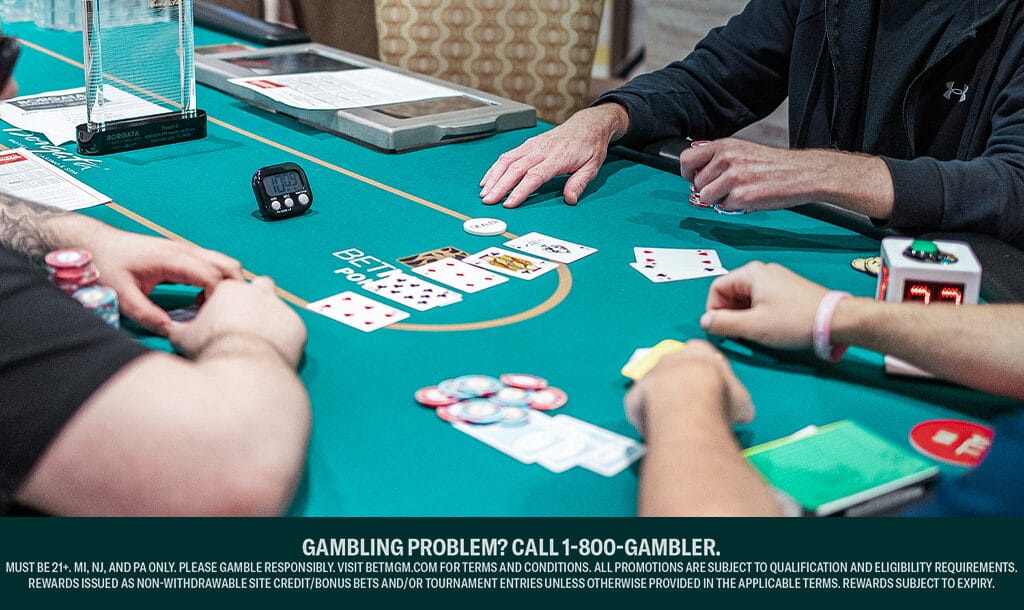Three poker players sitting at a poker table. There are five community cards on the table and one poker hand face up.