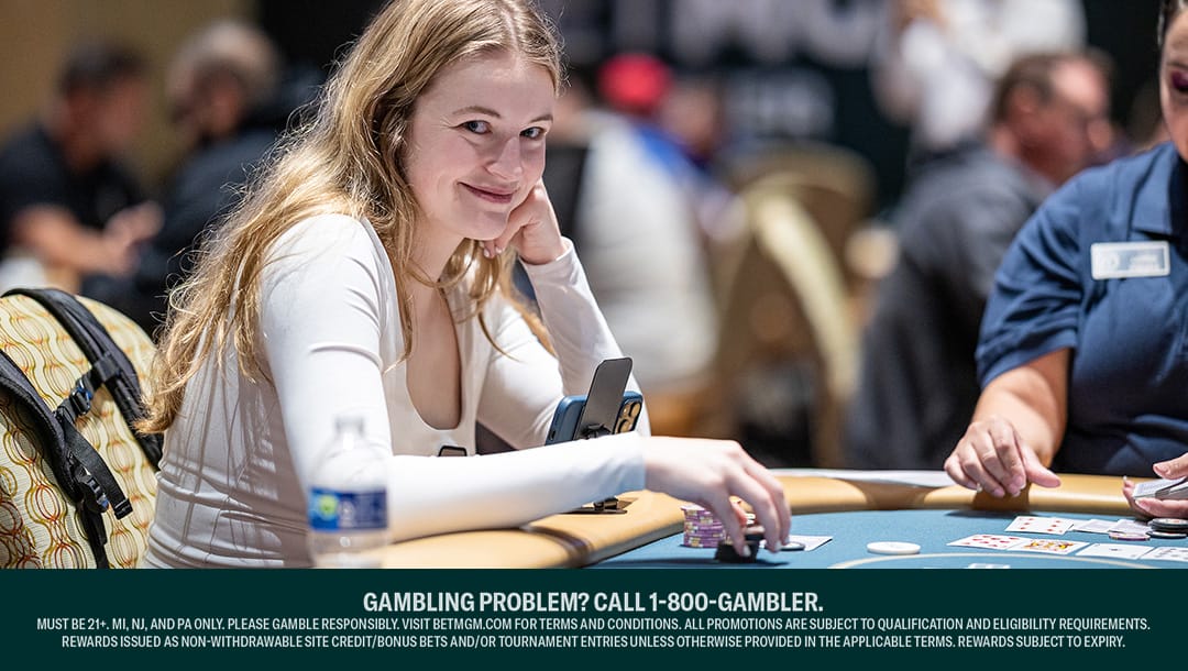 Abby Merk smiles while holding her poker chips at a poker table.