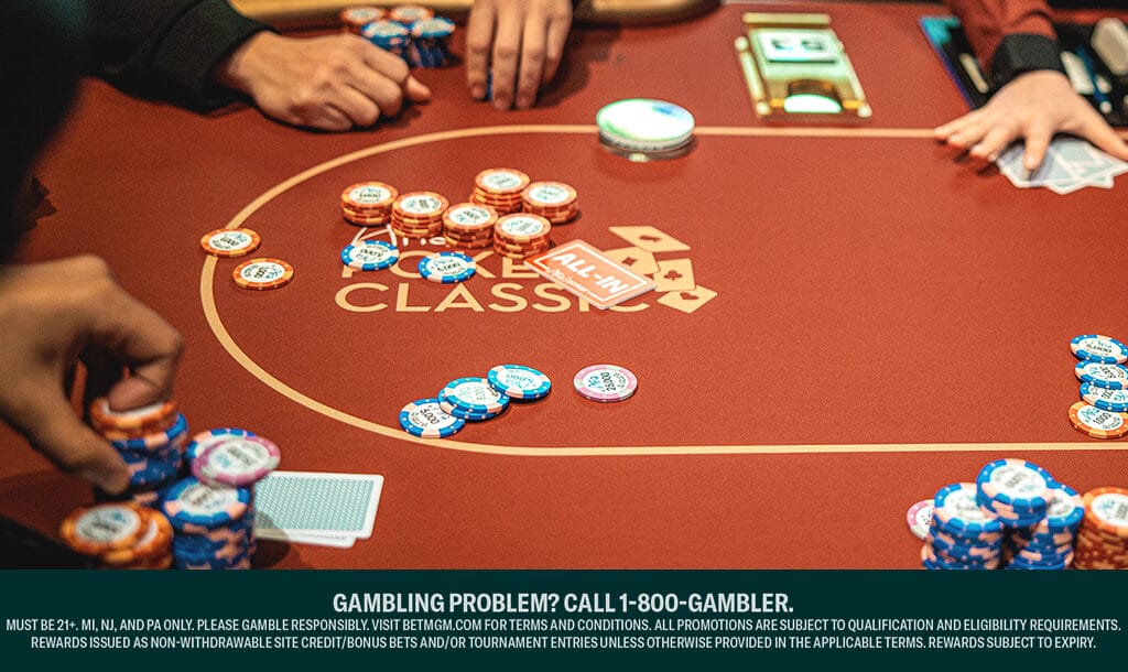 A view of a red poker table at the Aria Poker Classic. There are face-down cards and stacks of poker chips around the table, with players deciding their bets.