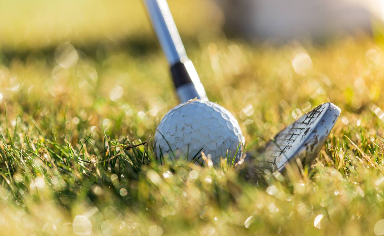 Close up golf ball with club on green grass