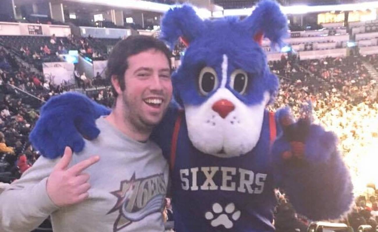 Fan posing with Philadelphia 76ers team mascot Franklin The Dog