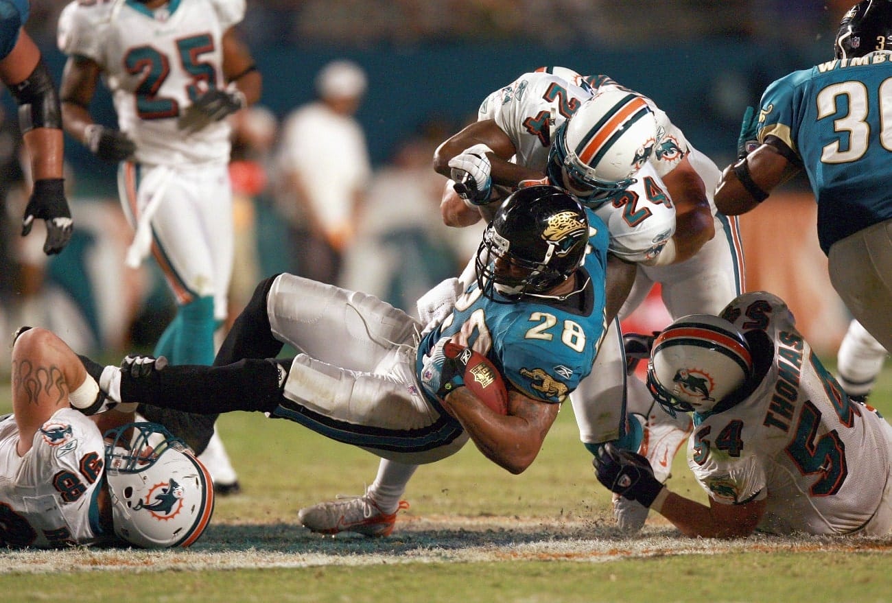 David Richardson #26 of the Jacksonville Jaguars grips the ball as he is tackled by Matt Roth #98 and Renaldo Hill #24 of the Miami Dolphins at Dolphin Stadium on December 3, 2006 in Miami, Florida