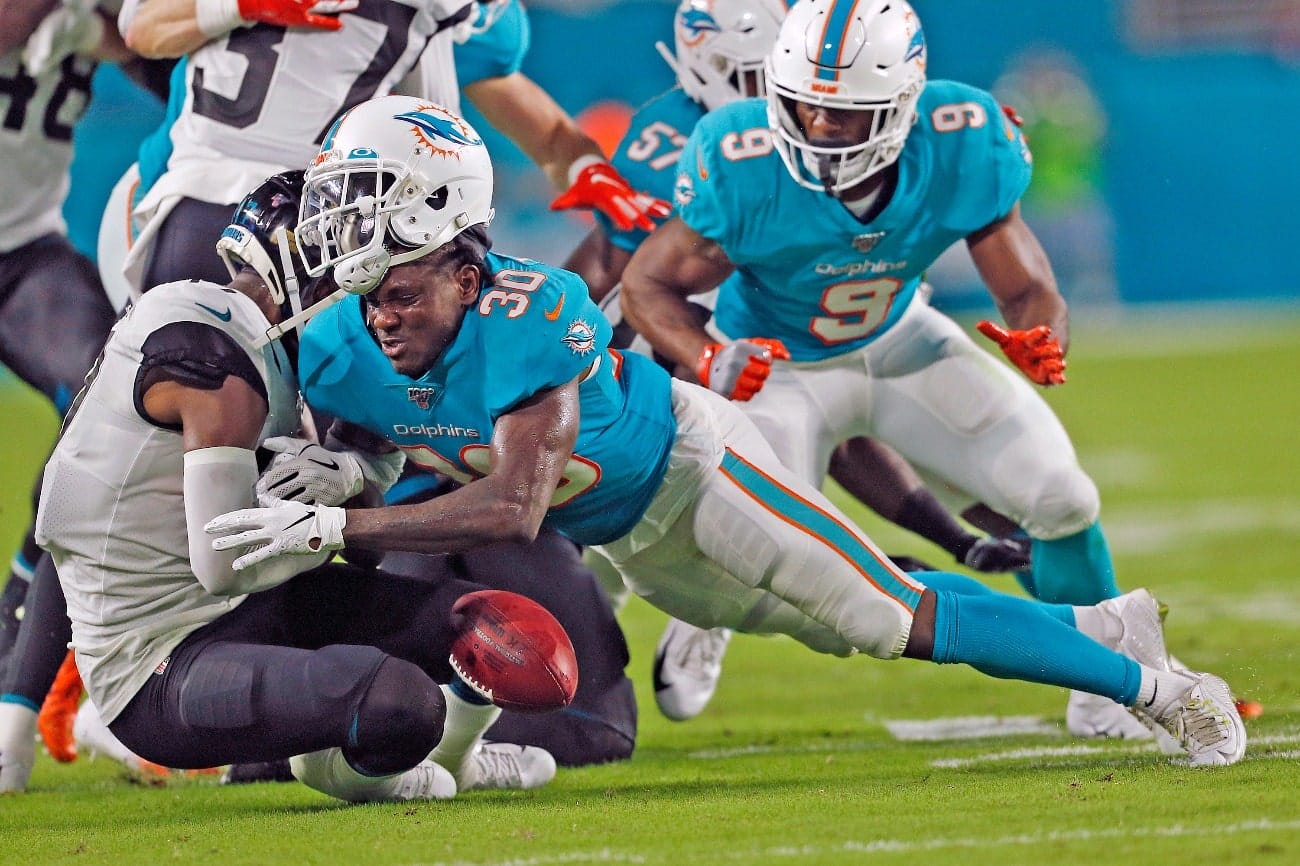 Chris Lammons #30 of the Miami Dolphins has his helmet knocked off as he tackles D.J. Chark #17 of the Jacksonville Jaguars during an NFL preseason game on August 22, 2019 at Hard Rock Stadium in Miami Gardens, Florida